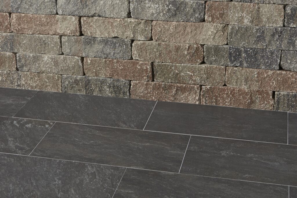 Concreto Antracita Terrassenplatten vor einer Mauer